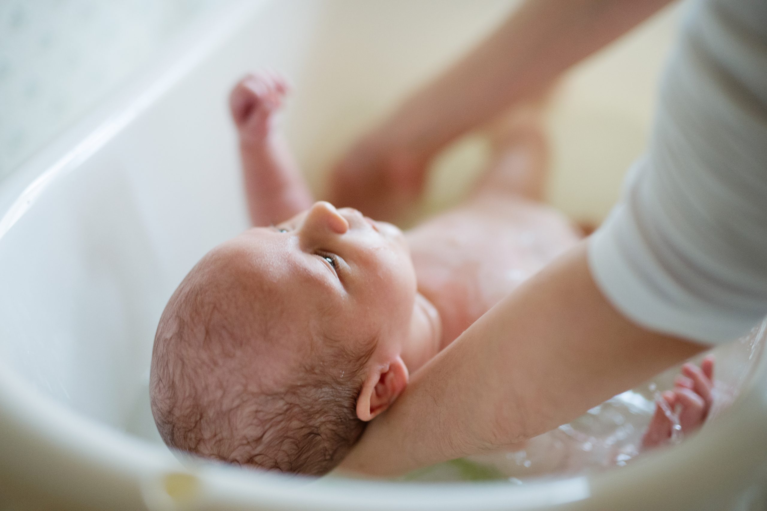 Unrecognizable,Mother,Bathing,Her,Son,In,White,Small,Plastic,Bat